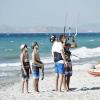 Cours de kitesurf au bord de la plage sur le sable avec une eau turquoise, trois garçons et un professeur de kitesurf