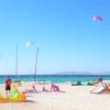 Spot à Kos au centre Horizon Surfing avec des voiles de kitesurf, une eau turquoise, des catamarans, des kiteurs, une vue sur les montagnes, un sable blanc et un ciel bleu