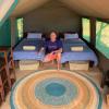 Chambre dans la tente de l'hôtel ecolodge Babaomby à Madagascar en pleine nature avec deux lits une place, des tables de chevets en bois et un tapis coloré