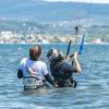 Cours de kitesurf dans l'eau sur le spot de Urla en Turquie avec une monitrice qui tient son élève par le harnais