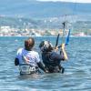 Cours de kitesurf dans l'eau sur le spot de Urla en Turquie avec une monitrice qui tient son élève par le harnais