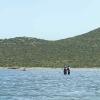 Cours de kitesurf dans l'eau sur le spot de Urla en Turquie avec un moniteur et son élève avec une coline derrière