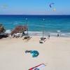 Spot à Kos en Grèce, au centre Horizon Surfing, avec du sable blanc, une eau turquoise, des kiteurs, des catamarans, et une vue sur les montagnes 