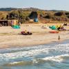 Spot de kitesurf à Kos en Grèce, au centre Horizon Surfing, pendant le coucher du soleil, avec des voiles de kitesurf, un enfant au bord de la plage et un apéro au centre