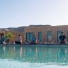 Cours de yoga et meditation devant la piscine d'eau turquoise et les bungalows de l'hôtel ecolodge la Tour d'Eole en bois avec des baies-vitrées qui offre une vue sur la lagune avec un arrière-plan de dune de sable