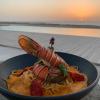 Repas gastronomique au bord de la pisicine durant un coucher de soleil avec une vue sur l'océan en fin de journée