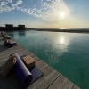 Cours de yoga avec un tapis et une brique devant la piscine de la Tour d'Eole avec une vue sur la lagune de Dakha en fin de journée et un ciel bleu