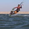 Kitesurfeuse en twintip sur le spot flat de Dakhla Lassarga derrière les dunes de sable du Sahara et avec une eau bleue