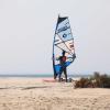 Windsurfeur qui se prépare à aller sur le spot de Dakhla Lassarga avec du matériel Duotone de ION Club sur le sable du désert du Sahara