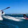Deux windsurfeurs en action sur une vague sur le spot de Madagascar avec un ciel bleu