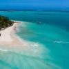 Vue aerienne d'une île et son sable blanc à Madagascar avec deux windsurfeurs naviguant sur le lagon avec une eau bleu truquoise et transparante