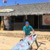 Gérant du centre Babaomby avec une planche de windsurf sur le sable