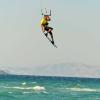 Kitesurfeur qui saute au dessus de l'eau turquoise et face à des montagnes à Kos en Grèce