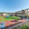 Terrain de jeu pour enfants avec balançoires autour de palmier et d'herbe sous un ciel bleu au sein de l'hôtel Horizon Beach Resort à Kos en Grèce