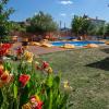 Espace piscine de l'hôtel Urla Surf House avec une grande piscine, de la végétation, des fleurs de couleurs et un espace chill avec des poufs