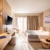 Chambre standart beige de l'hôtel Horizon Beach Resort à Kos en Grèce avec un lit deux places, une télévision et une terrasse illuminée