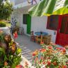 Terrasse d'une chambre de l'hotel Urla Surf House avec une table en bois, une porte rouge, des palmiers et des fleurs rouges et roses autour